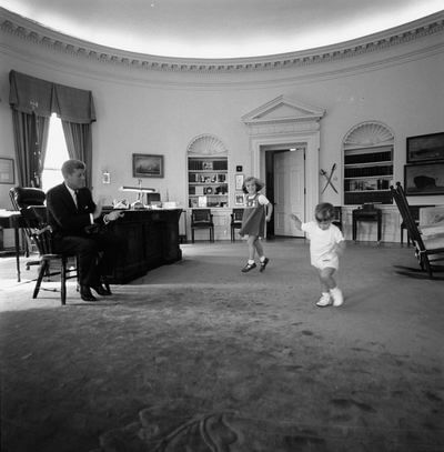President John F. Kennedy claps while his children, Caroline Kennedy and John F. Kennedy, Jr., dance in the Oval Office of the White House, Washington, D.C.